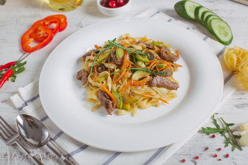 Pasta with olive meat greens on a white plate