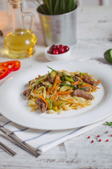 Pasta with olive meat greens on a white plate