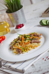 Pasta with olive meat greens on a white plate