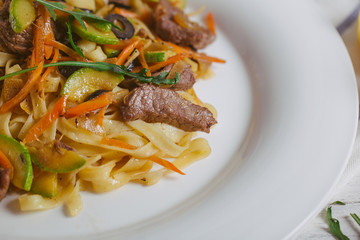 Pasta with olive meat greens on a white plate