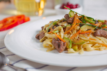 Pasta with olive meat greens on a white plate