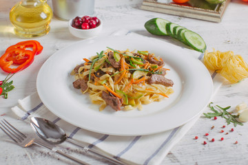 Pasta with olive meat greens on a white plate