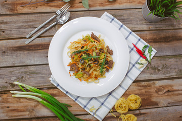 Pasta with olive meat greens on a white plate