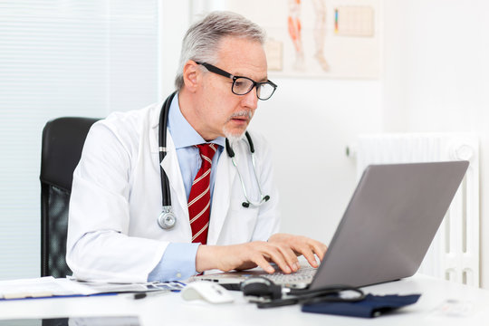 Portrait of a mature doctor using his laptop computer