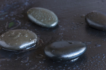 black stones with water drops on a black slate background