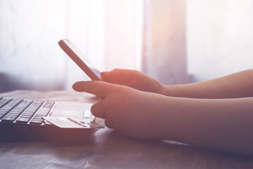A woman holds a smartphone sitting at the table. vintage effect