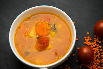 close up on soup with tomato, lentil and potato, rustical background, top view