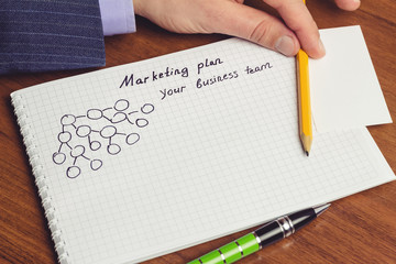 Man shows presentation of business concepts network marketing and business structures diagram in notepad on the table.