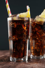 Softdrink with ice cubes, lemon and straw in glass
