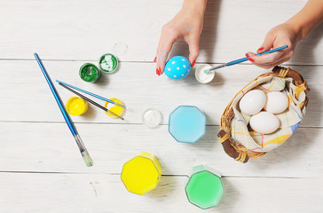 Girl decorating Easter eggs. rustic white background
