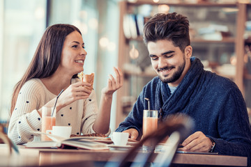 Happy young couple having breakfast in cafe