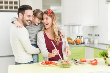 Poster Happy young family preparing lunch in the kitchen © ivanko80