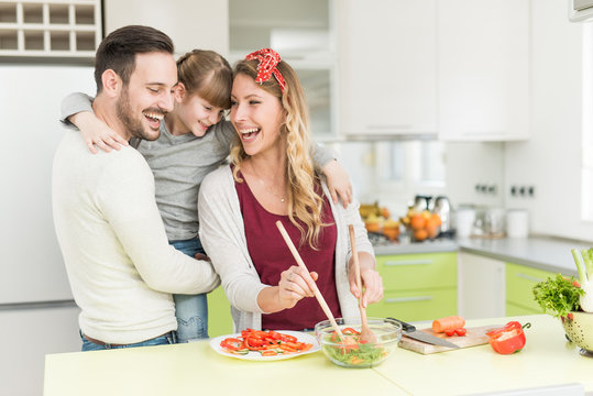 Happy young family preparing lunch in the kitchen