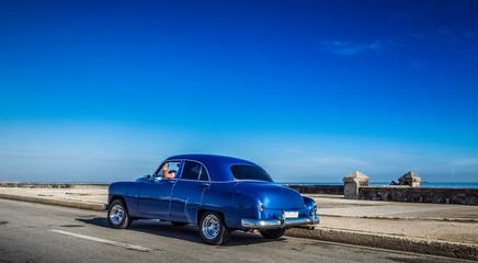 Fototapeta na wymiar HDR - Blauer Oldtimer fährt auf der berühmten Promenade Malecon in Havanna Kuba - Serie Kuba Reportage