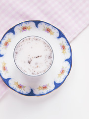 Chia pudding with chia seeds and milk on decorative plate with pink checked cloth on white background 