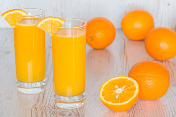 Fototapeta na wymiar orange juice in glasses at light wooden background