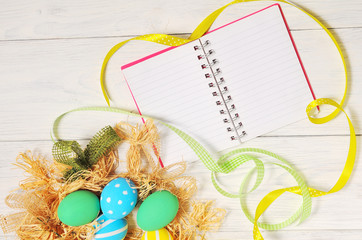 Notebook with eco Easter eggs in the nest on rustic white background