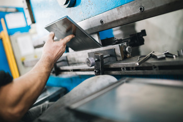 Metallurgy heavy industry. Factory for production of heavy pellet stoves and boilers. Worker hands close up. Extremely dark conditions and visible noise. Focus on foreground.