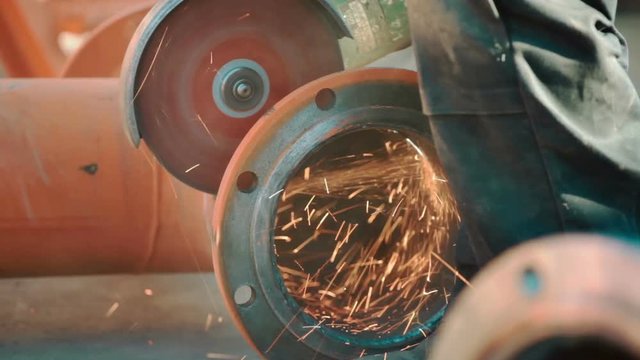 Worker grinds metal construction with circular saw