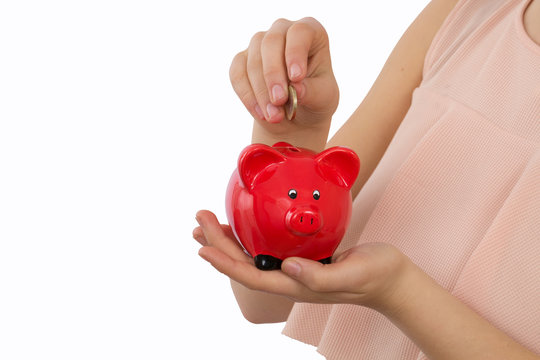 Junge Frau steckt Euro Münze in ein rotes Sparschwein auf weißem Hintergrund freigestellt
