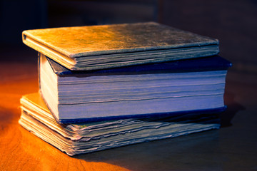 Old books on a table in the dark living room, vintage style