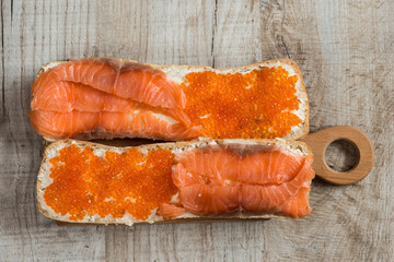 sandwiches with red caviar and salmon on wooden background