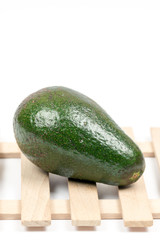 Whole green avocado on the wooden background