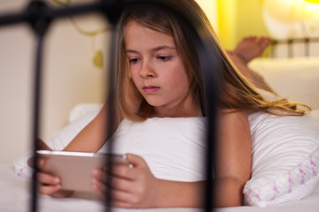 Young girl using smartphone in bed