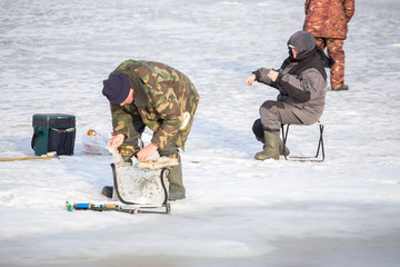  Fishermen on the river catch fish on ice floe in the spring. The danger of falling under the ice. Near the water from melted ice
