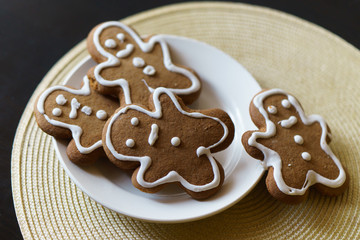 gingerbread men on a white plate on black background
