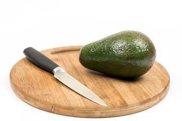 Avocado fruit on the wooden kitchen board with knife