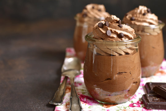 Chocolate mousse with whipped cream in a vintage glass jar.