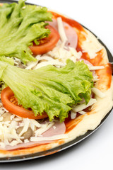 Preparing pizza with lettuce and tomato over white background