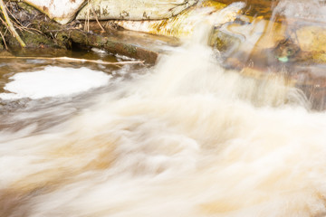 Spring bubbling stream, flow of water in motion, unfocused abstract background of nature