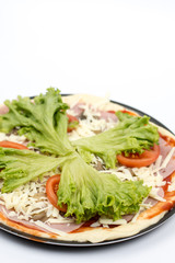 Preparing pizza with lettuce and tomato over white background
