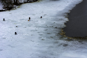 Fishermen on the river in winter ice fishing before the ice melting