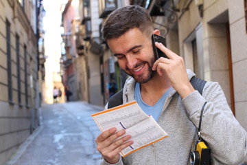 Tourist calling by phone while looking at tourism guide or dictionary 