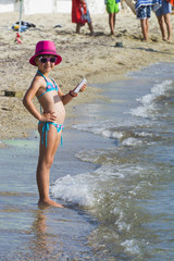 Little girl with tablet on beach during summer vacation