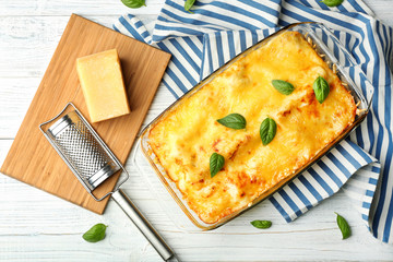 Traditional lasagna in glass baking dish and blue striped napkin on table