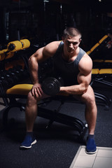Fototapeta na wymiar Young handsome man with dumbbell training in gym