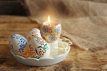 Easter concept. Decorated eggs with candle on rustic table, closeup