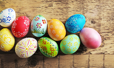 Naklejka na ściany i meble Colourful Easter eggs with floral ornament on wooden background, closeup
