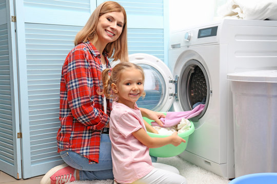 Pretty woman and her daughter doing laundry at home
