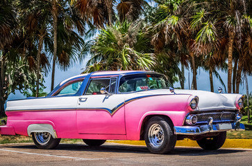 HDR -  Weiß rosa amerikanischer Oldtimer parkt unter Palmen nahe des Strandes in Varadero Kuba - Serie Kuba Reportage