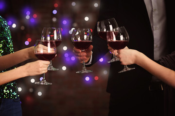 People clinking glasses at party against defocused lights