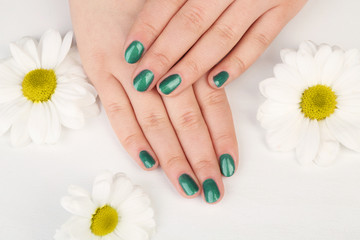 Obraz na płótnie Canvas Nail art concept. Beautiful female hands with manicure and flowers on white wooden background