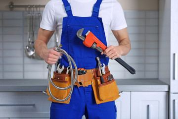 Handsome young plumber in kitchen, closeup