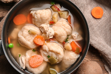 Stewpan with delicious chicken and dumplings on table