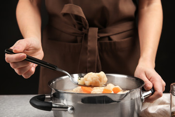 Female hands holding spoon above pan of delicious chicken and dumplings
