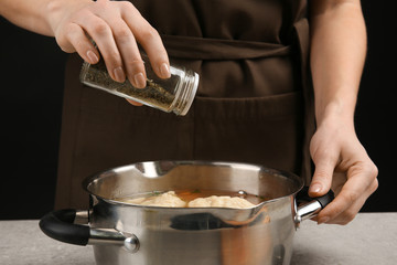 Female hands adding herbs into pan with delicious chicken and dumplings
